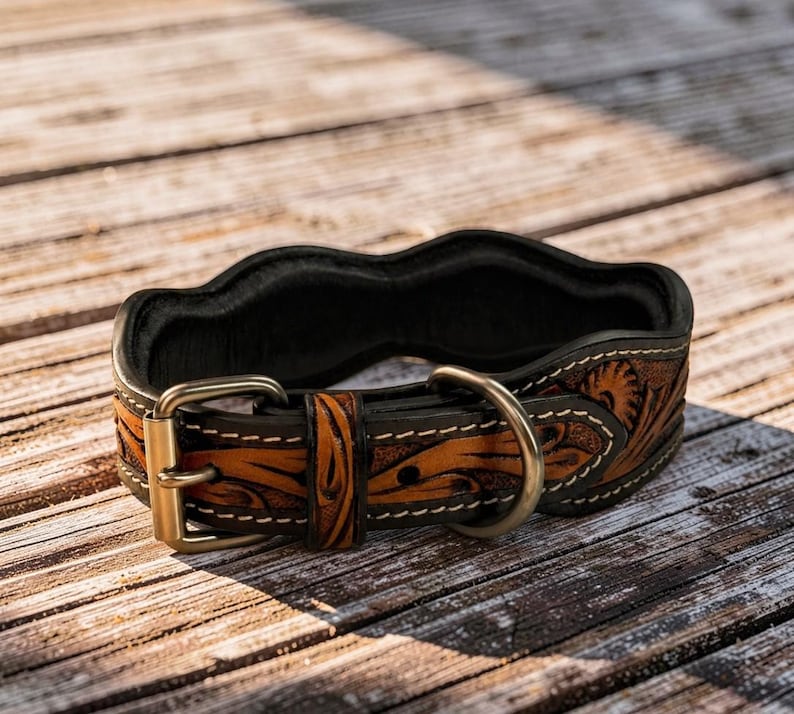 Peut inclure: Un collier de chien en cuir marron et noir avec un motif floral d&eacute;coratif. Le collier est dot&eacute; d'une boucle en laiton et d'un anneau en D pour l'attache de la laisse. Le collier mesure environ 2.5 cm de large.