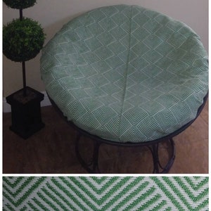Pu&ograve; includere: Un cuscino rotondo per sedia con un design geometrico verde e bianco. Il cuscino &egrave; fatto di tessuto.