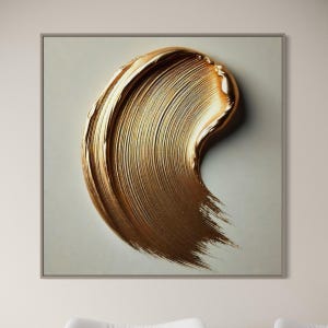 May include: A framed canvas print showing a large, textured brushstroke of gold paint. The metallic gold paint is swirled across the canvas, creating a dynamic and artistic effect. The artwork is set against a neutral background.
