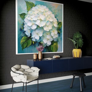 Könnte beinhalten: Ein Gemälde einer weißen Hortensie mit grünen Blättern vor blauem Hintergrund. Das Gemälde ist weiß gerahmt und hängt an einer schwarzen Backsteinwand. Vor dem Gemälde steht ein blauer Schrank mit einem weißen Stuhl und einem schwarzen Hocker.