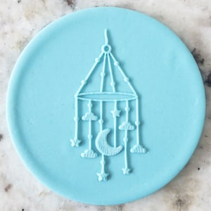 May include: A light blue silicone baby mobile mold with a crescent moon, stars, and clouds design.