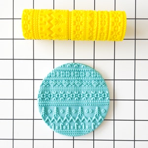 Puede incluir: Un juego de dos rodillos de silicona azul y amarillo con un patrón de copo de nieve y árbol de Navidad. Los rodillos se utilizan para decorar pasteles y galletas.