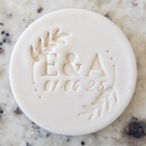 May include: White clay stamp with a leafy design and the initials "E & A" and the date "01.06.25".
