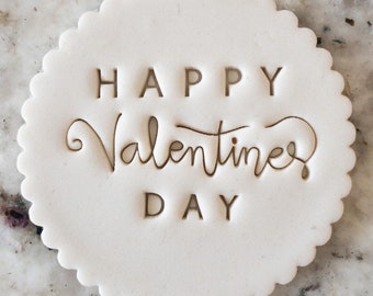 May include: White round cookie with the text "HAPPY VALENTINE'S DAY" embossed on the surface.