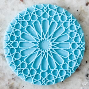 May include: A light blue round silicone stamp with a geometric design of stars and circles.