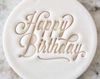 Op de afbeelding: Ronde witte cake-decoratiestempel met de woorden "Happy Birthday" in een cursief schrift.
