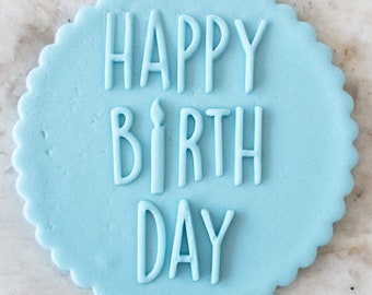 May include: A light blue round cake topper with the words "Happy Birthday" in white icing.