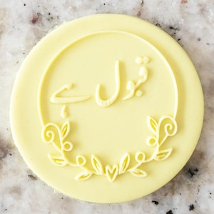 May include: A yellow circular cookie with a white circle in the centre. The white circle has a floral design around the edge and the text "شوال ہے" in the centre.
