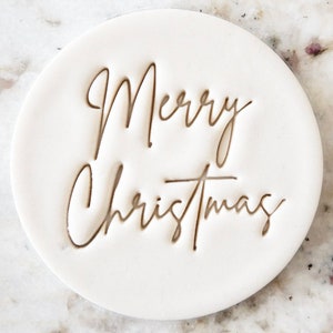 May include: White ceramic stamp with the text "Merry Christmas" in a cursive font.