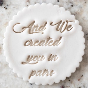 以下が含まれることがあります： 中央に「And We created you in pairs」という文字が浮き彫りになった、白い丸いクッキーカッターです。