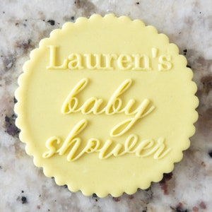 May include: A yellow round cake topper with the text "Lauren's baby shower" in white.