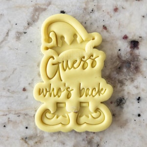 Puede incluir: Cortador de galletas de plástico amarillo con forma de elfo con sombrero y el texto "Guess who's back".