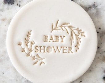 Puede incluir: Cortador de galletas redondo blanco con las palabras "BABY SHOWER" y un diseño floral.