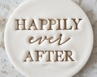 Pode incluir: Carimbo redondo de cerâmica branco com o texto "Happily ever after" em relevo na superfície.