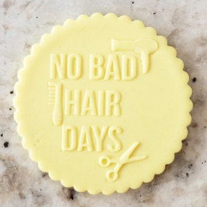 May include: A yellow round cookie with the text "NO BAD HAIR DAYS" and images of a hairdryer, comb, and scissors.