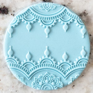 May include: A light blue silicone cake decorating stamp with a detailed mandala design. The stamp features a repeating pattern of intricate floral and geometric shapes.