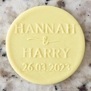 Può includere: Un biscotto rotondo giallo con il testo "HANNAH & HARRY 26.03.2023" in rilievo.