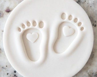 Puede incluir: Kit de huellas de cerámica blanca con dos huellas de pies de bebé y corazones.