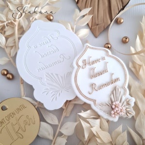May include: Two white silicone moulds for baking, one with the text "Have a blessed Ramadan" and the other with the text "Have a blessed Ramadan" in Arabic. The moulds are shaped like a traditional Islamic arch.