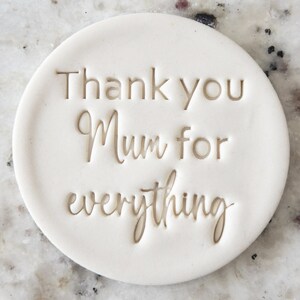 以下が含まれることがあります： 「Thank you Mum for everything」という金色の文字が刻まれた、白いセラミック製の丸いコースターです。
