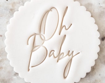 May include: White round cookie cutter with a scalloped edge. The cutter is embossed with the text "Oh Baby" in a cursive font.