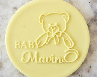Könnte beinhalten: Ein runder gelber Keks mit einer weißen Umrandung eines Teddybären und dem Text "BABY Mawin"