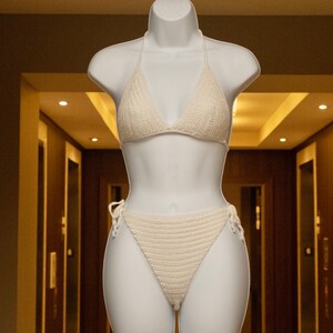 May include: A white crocheted bikini top and bottom. The bikini is on a white mannequin.
