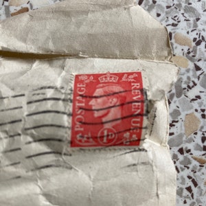 May include: A red postage stamp with a portrait of a man and the text "POSTAGE REVENUE 1p" in black.
