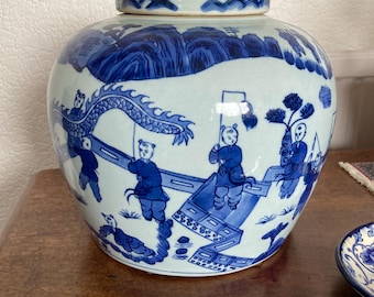 Puede incluir: Un jarrón de porcelana azul y blanco con tapa. El jarrón está decorado con una escena de niños jugando con una cometa de dragón. El jarrón es un diseño chino tradicional.