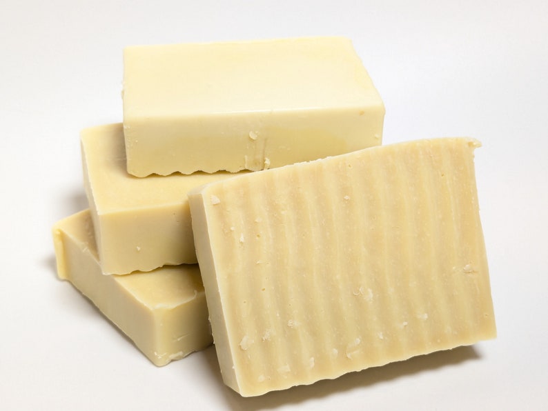May include: A stack of four rectangular bars of off-white soap. The bars have a smooth, solid appearance with a subtle wavy, ridged texture on the front-facing surface of the foremost bar, while the other bars appear smooth and flat.