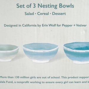 May include: A set of three nesting bowls, ideal for salad, cereal, or dessert. The bowls are painted in shades of blue and white. The text at the top reads "Set of 3 Nesting Bowls". Designed in California.