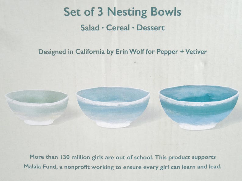 May include: A set of three nesting bowls, ideal for salad, cereal, or dessert. The bowls are painted in shades of blue and white. The text at the top reads "Set of 3 Nesting Bowls". Designed in California.