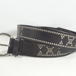 May include: Black leather belt with silver-colored stud accents. The belt features a silver-toned buckle and is decorated with rows of studs and studded Roman numerals. A stylish accessory.