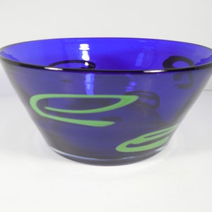 May include: A cobalt blue glass bowl with green and black abstract designs.
