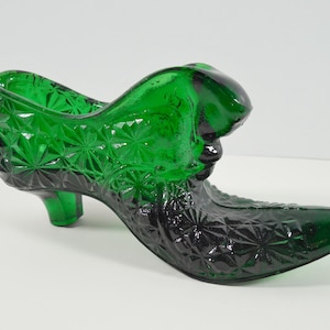 May include: A green glass shoe shaped dish with a starburst pattern.