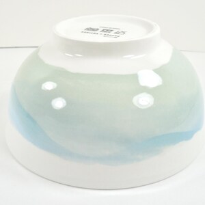 May include: A white ceramic bowl with a rounded shape, featuring a watercolour design in shades of blue and green. The bowl has a glossy finish and a smooth aesthetic, suitable for serving food.