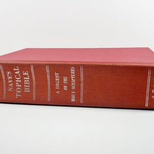 May include: A red hardcover book titled "Nave's Topical Bible" with silver lettering. The book also includes the text "A Digest of the Holy Scriptures" and the initials "A & P A".