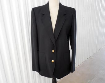 May include: A black blazer with a notched lapel and two gold-colored buttons. The blazer has two front pockets and is displayed on a mannequin. The garment is a classic style, suitable for various occasions.