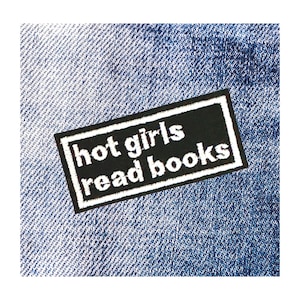 May include: Black and white iron-on patch with the text "hot girls read books" on a blue denim background.