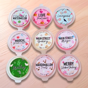 May include: Nine round, pink and clear wax melt containers with various labels. Labels include "I Carried a Watermelon," "Love Potion," and "Lovegood." Each container is labeled "100% Soy Wax."