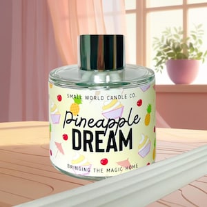 May include: A clear glass candle jar with a silver lid, labelled "Pineapple Dream" with illustrations of pineapples and desserts. The text "Small World Candle Co." and "Bringing the Magic Home" are also visible.