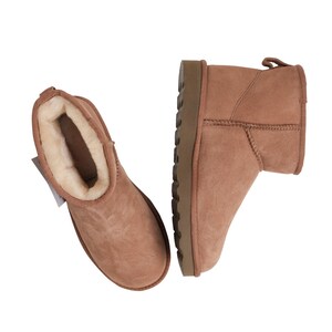 May include: A pair of brown suede ankle boots with a sheepskin lining. The boots have a brown rubber outsole.