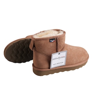May include: Brown suede shearling boots with a white shearling lining. The boots have a black rubber sole and a tag that says "Maison Joseph 100% Mouton".