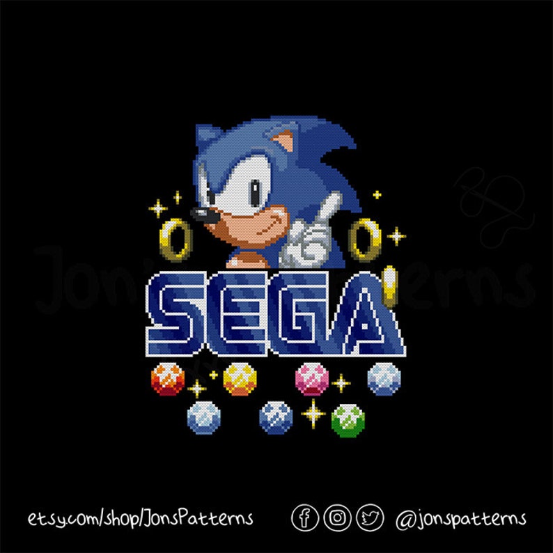May include: A pixelated image of Sonic the Hedgehog, a blue video game character, with a gold ring and the word "SEGA" in blue and white letters. There are seven colorful gems below the word "SEGA".