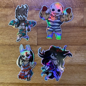 May include: Four iridescent holographic stickers featuring characters from a horror video game. The stickers are on a wood surface. The characters are a masked man with a striped shirt, a masked woman with a white shirt, a masked man with a green shirt, and a masked woman with a purple shirt.