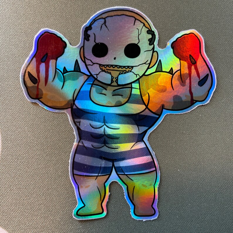 May include: A holographic sticker of a cartoon character with a large, muscular body wearing a blue and white striped swimsuit. The character has a large, white mask with a toothy grin and is flexing both arms.