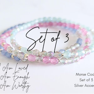 May include: Set of three delicate beaded bracelets in shades of blue, pink, and white with silver accents. The bracelets feature the text "I Am Loved", "I Am Enough", and "I Am Worthy".