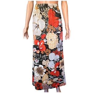 May include: A long, flowing skirt with a floral print in shades of red, orange, white, and brown on a dark green background.