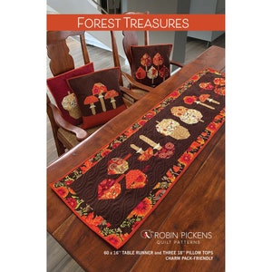 May include: A table runner and three pillow tops with a forest theme. The table runner is 60 inches long and 16 inches wide, featuring leaf and mushroom appliqués. The pillows are 18 inches square, with similar designs. The text "FOREST TREASURES" is at the top.