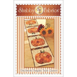 May include: A patchwork pumpkin table runner with four pumpkin designs. The runner is made of orange, brown, and cream fabrics. The text "Shabby Fabrics" is at the top. The words "Patchwork Pumpkin Table Runner" are at the bottom.